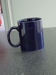 A plain dark-blue mug with a visible handle sitting on a gray countertop.