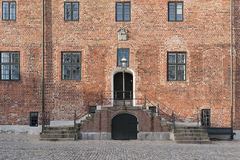 The facade of a red-brick building with dark windows and a central entrance.