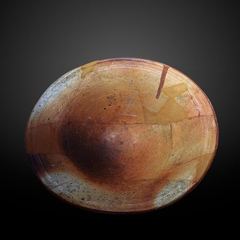 A shallow mottled brown ceramic dish photographed against a dark background.