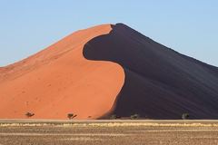 An orange sand dune with a sharply contrasting shaded slope.