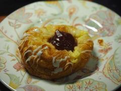 A glazed pastry with a dark center on a patterned plate.