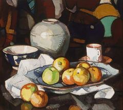 A painted still life with fruit, a white jar, cups and patterned fabric.