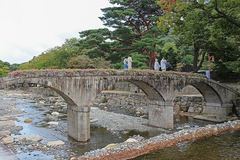 A low stone bridge with multiple arched openings crossing a rocky stream.