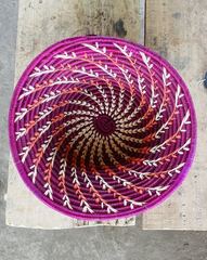 A round purple woven basket with a repeating spiral pattern and lighter strands.